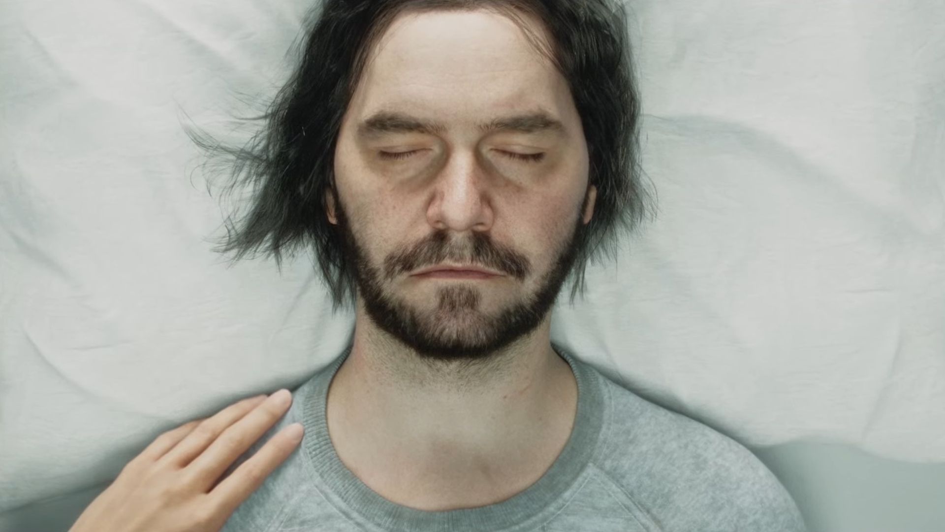 Dylan asleep with a hand touching his shoulder during the trailer for Control 2.